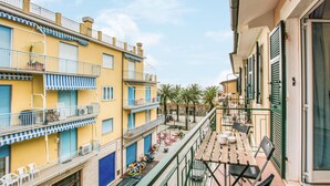A narrow street with buildings on either side, balconies with railings, and a table with chairs on the right side. - 2 bedroom awesome apartment in Moneglia (Moneglia)