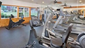Un gimnasio con varias cintas de correr, elípticas y una bicicleta estática.