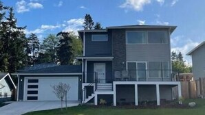 A modern two-story house with a garage, a covered front porch, and a well-maintained lawn.
