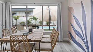 A dining area with a view of a pool and palm trees.