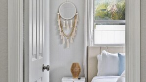 A bedroom with a bed, bedside table, and a window with a view of greenery.