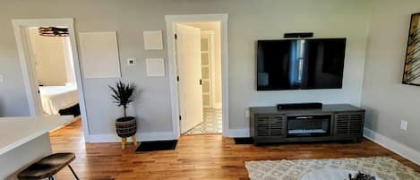 Una sala moderna con un televisor de pantalla plana, una pequeña zona de bar y una escalera que lleva a otra habitación.