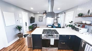 Et moderne køkken med en central ø, rustfrie stålemmer og et backsplash med fiskebensmønster.
