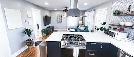 Cozinha moderna com ilha central, eletrodomésticos de aço inoxidável e backsplash com padrão herringbone.