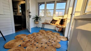 A room with a blue floor, a large woven rug, a potted plant, and a bench with cushions. - [C] Private Country Retreat 10 Acres + 4 Min to Lawrence (Lawrence)