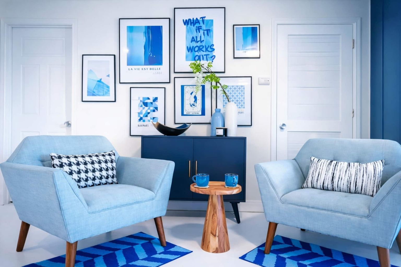Una sala moderna con dos sillones azul claro, una mesa de centro de madera y una alfombra estampada en tonos azules.