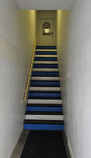 A staircase with alternating blue and white steps leading to a door with a glass panel.