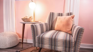 Una poltrona con rivestimento decorativo, un tavolino con una ciotola e una lampada.