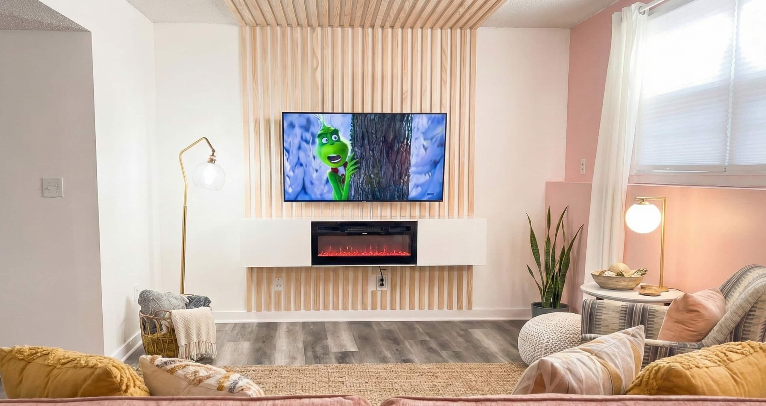Un salon moderne doté d’un téléviseur à écran plat fixé au mur, d’une cheminée en dessous et d’un coin salon confortable agrémenté de coussins.