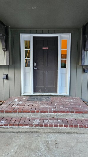 A front door with a 'NO SOLICITORS' sign, a mailbox, and a brick-paved entrance.
