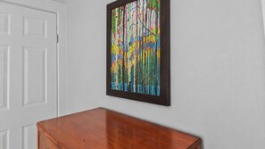 A room with a wooden table and a colorful abstract painting on the wall.