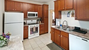 Una cocina con armarios de madera, un refrigerador, un microondas, una estufa y un lavavajillas.