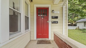 A red door with a mailbox and a house number.
