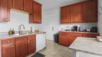 A kitchen with wooden cabinets, a dishwasher, a sink, and various appliances like a coffee maker and toaster.
