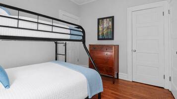 A bedroom with a bunk bed, a dresser, and a door.