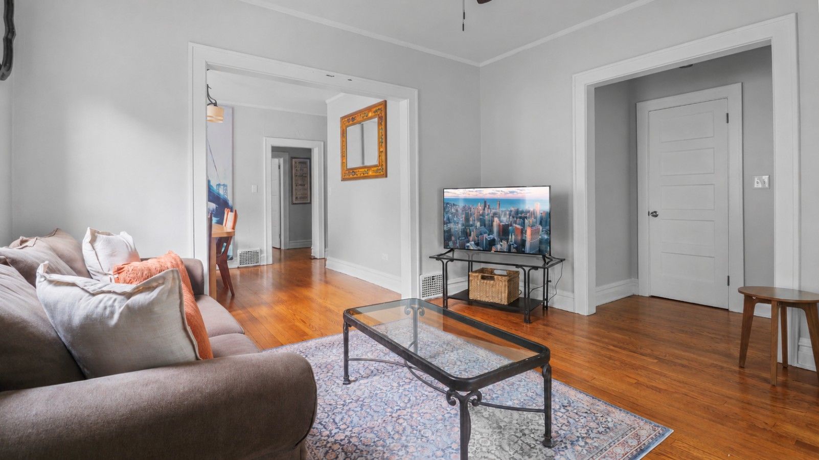 A living room with a sofa, a coffee table, a television on a stand, and a door.
