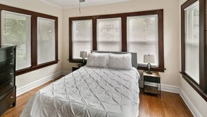 Un dormitorio con una cama, dos mesitas de noche, un aparador y un ventilador de techo.
