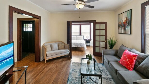 Una sala de estar con un sofá, una silla, una mesa de centro, un televisor y un ventilador de techo.