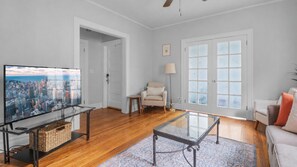 A living room with a television, a sofa, a coffee table, and a lamp.