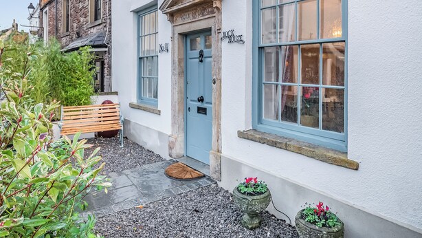 A building with a blue door, a window with a nameplate, and a bench outside.