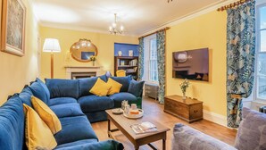A living room with a sectional sofa, a fireplace, a television, and a patterned curtain.