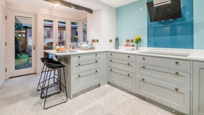 A modern kitchen with a large island, white cabinetry, and a blue accent wall.