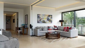A modern living room with a grey sectional sofa, a coffee table, and a large abstract painting on the wall.