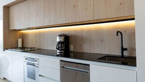 A modern kitchen with wooden cabinets, a stainless steel dishwasher, and a coffee maker.