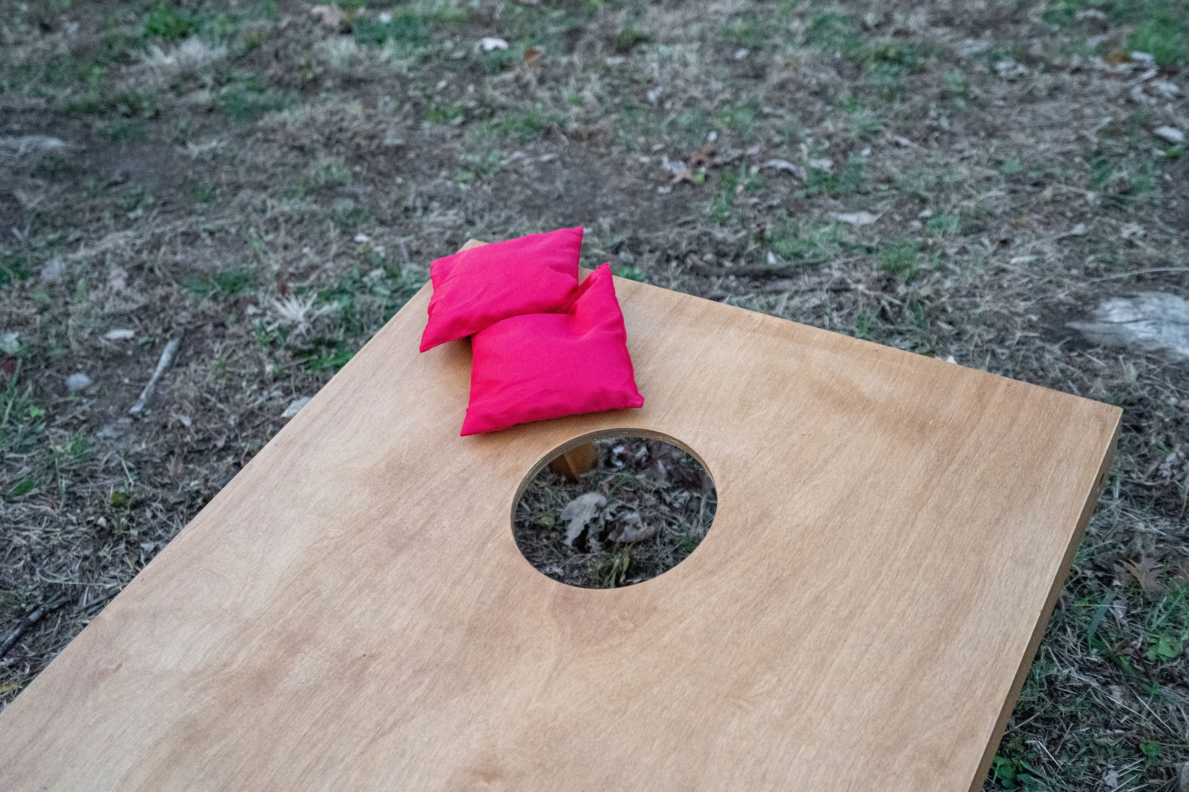 Una tabla de madera con un agujero circular y dos cojines rojos encima.