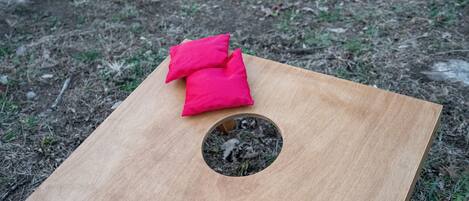 Una tabla de madera con un agujero circular y dos cojines rojos encima.