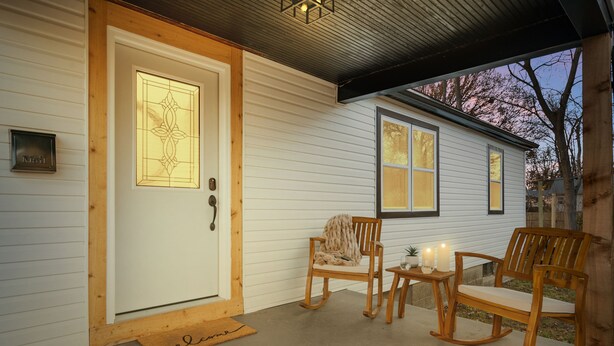 A wooden door with a glass panel, a mailbox, and a small table with candles. - Urban Oasis: A Charming Downtown Retreat with Game Room, Firepit and Yard Games (Evansville)