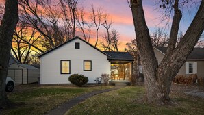 A single-story house with a front porch, a visible mailbox, and a well-maintained lawn. - Urban Oasis: A Charming Downtown Retreat with Game Room, Firepit and Yard Games (Evansville)