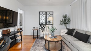 A modern living room with a sofa, a coffee table, a TV, and a fireplace. - Urban Oasis: A Charming Downtown Retreat with Game Room, Firepit and Yard Games (Evansville)