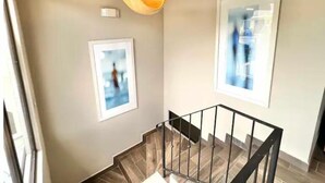 A staircase with a wooden railing and a hanging light fixture. - Apartment by Quepos Fishing
 (Quepos)