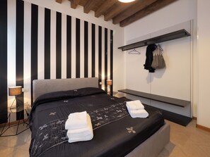 Relax in a spacious room with a large bed, bedside table, and convenient shelf.