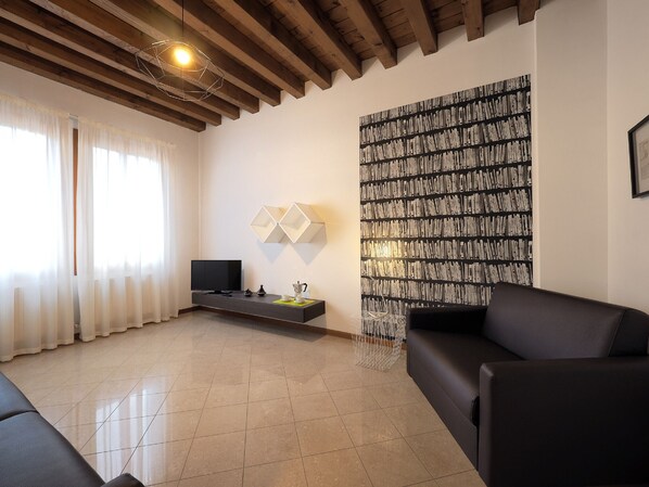 Relax in this stylish living room with a flat-screen TV, black leather sofa, and geometric pendant light.