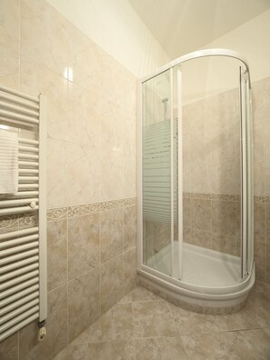Enjoy a refreshing shower in the glass-enclosed shower stall with a towel rack nearby.