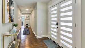 Un couloir avec une console en verre, un tapis et une porte dont les panneaux sont en verre dépoli.