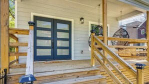 Une terrasse en bois avec une porte bleu foncé, un escalier en bois et une lanterne suspendue.