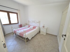Une chambre à coucher avec un lit, des tables de chevet, une fenêtre et une porte.