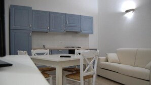 A compact kitchen with white cabinets and a dining area with a white table and chairs.