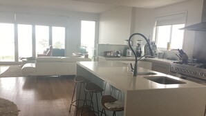 Uma cozinha moderna com uma ilha grande, banquetas e fogão a gás.