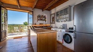 Una cocina con suelo de madera, lavadora integrada y una isla grande.