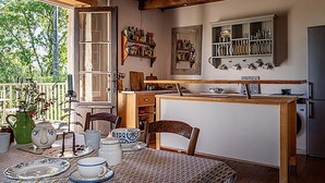 Una cocina acogedora con vigas de madera, una mesa de comedor dispuesta con vajilla y vistas al exterior.