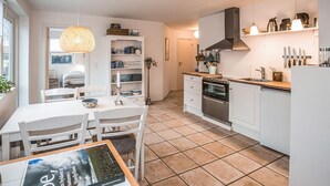 A modern kitchen with white cabinets, a stove, and a dining area with a table and chairs.