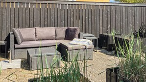 An outdoor seating area with a wicker sofa, a small table, and a bench.