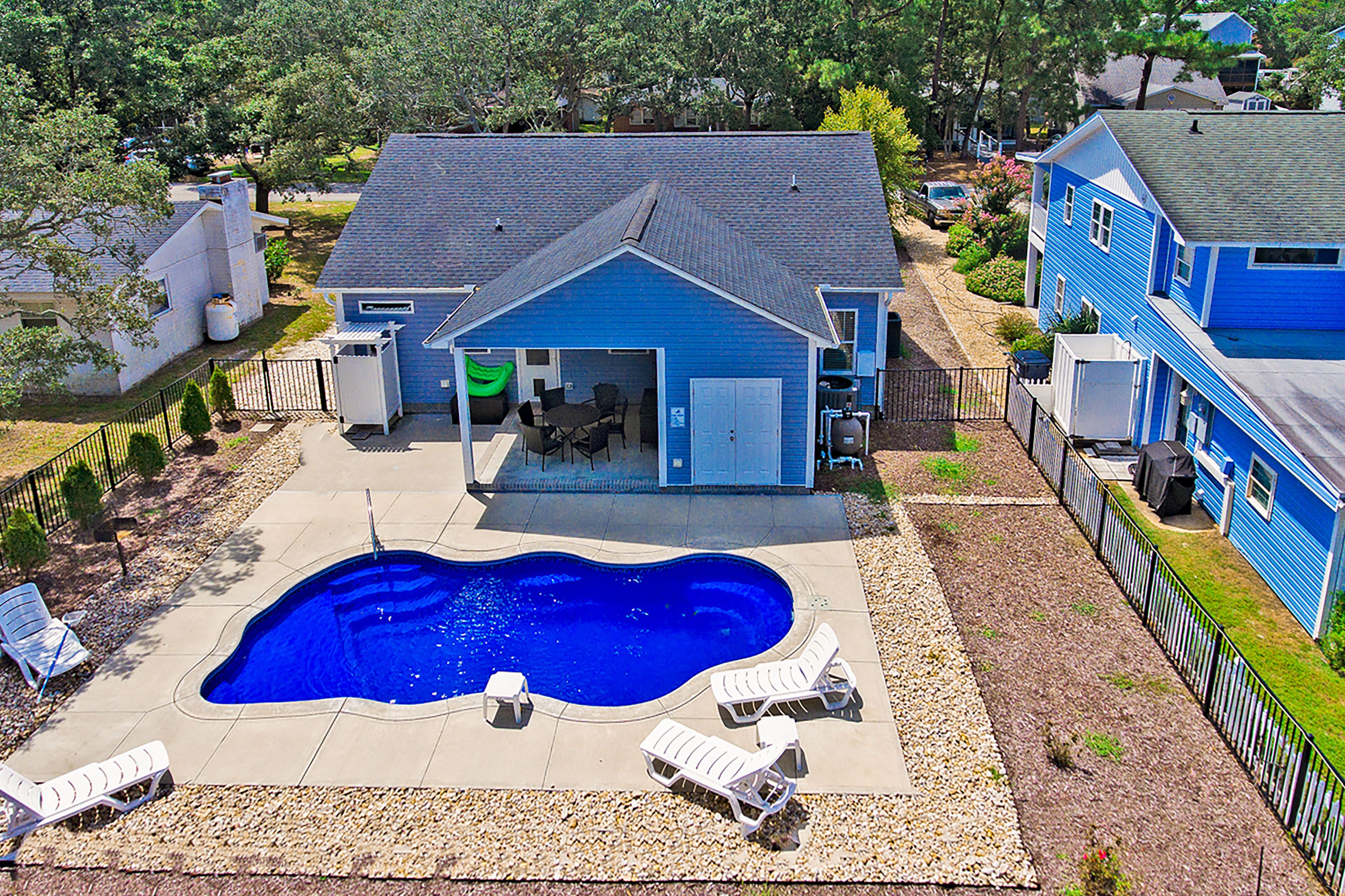 A residential property with a swimming pool, outdoor seating, and a garage.