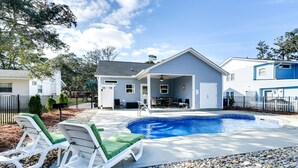 A residential setting with a swimming pool, two lounge chairs, and a covered patio area. - Serene Oak Island Home w/ Private Saltwater Pool! (Oak Island)