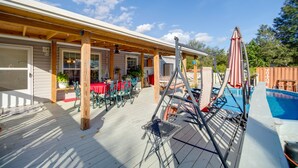 Un patio cubierto con mobiliario exterior, piscina y una terraza de madera.