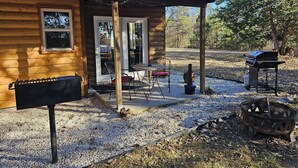Een houten chalet met een veranda, een barbecue en een vuurplaats.